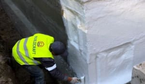 Професіонал з Білдкрафт наносить гідроізоляційне покриття на стіну підвалу.